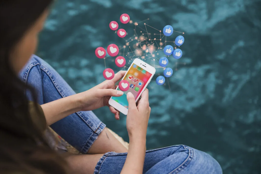 Frau, die ein Handy mit Symbolen der sozialen Medien Instagram, TikTok und Facebook hält